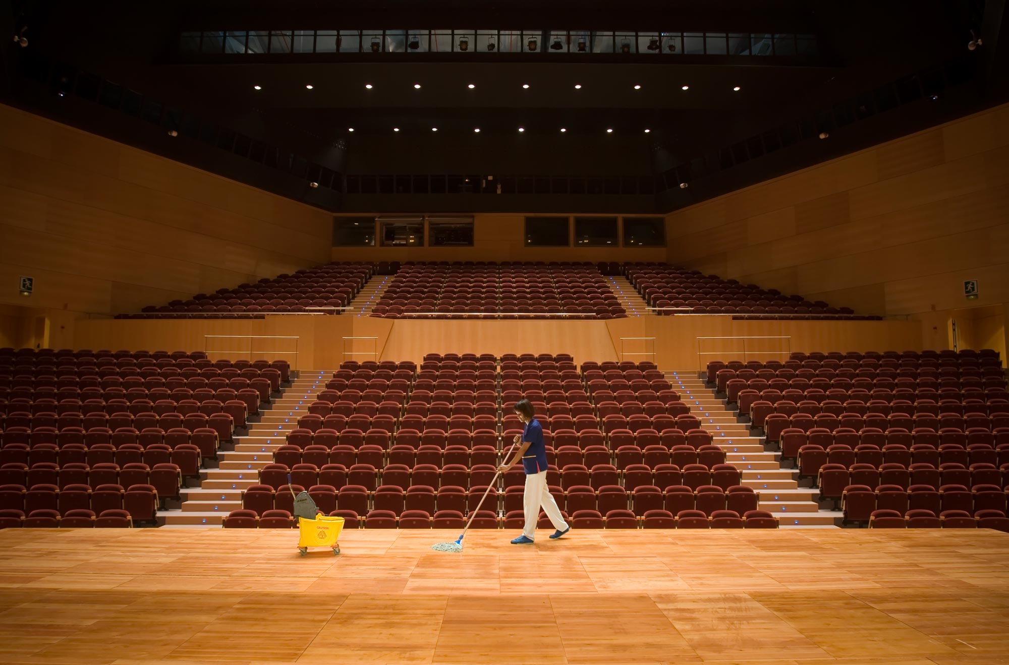 female worker cleaning stage auditorium